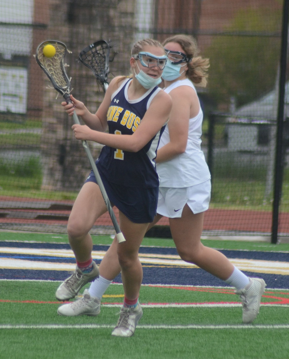 Pine Bush’s Alexandra Watkins carries the ball forward as Newburgh’s Mikayla Marrero defends during a girls’ lacrosse game at Academy Field in Newburgh on May 10.