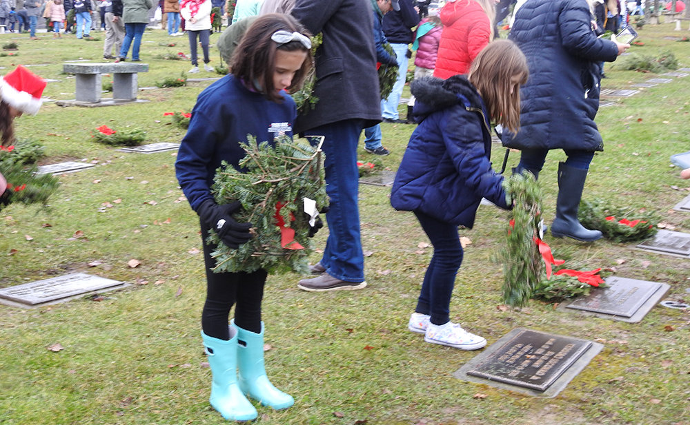 Volunteers lay wreaths at graves of Veterans.