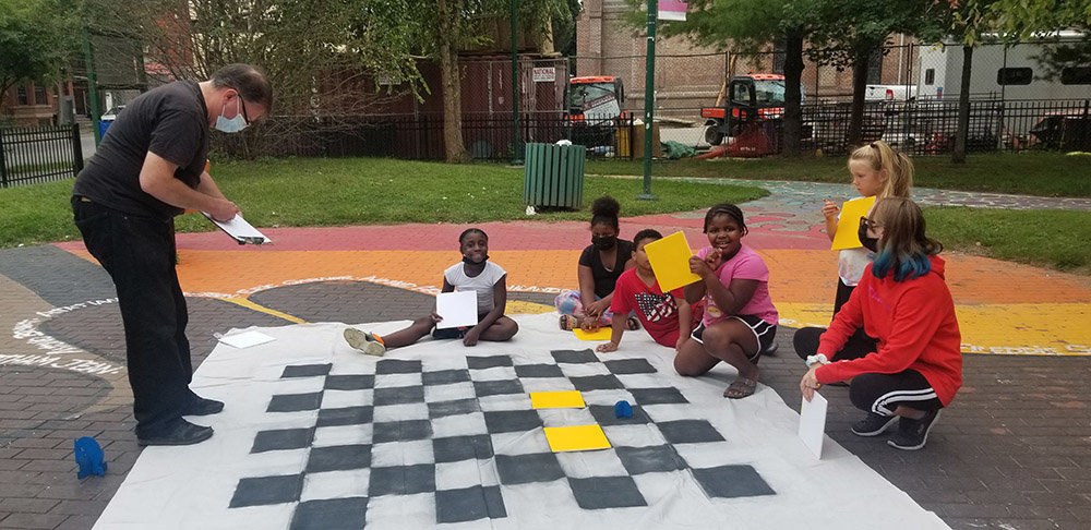 The Crossroads Chess Community meets at a local park to play chess on a homemade outdoor board.