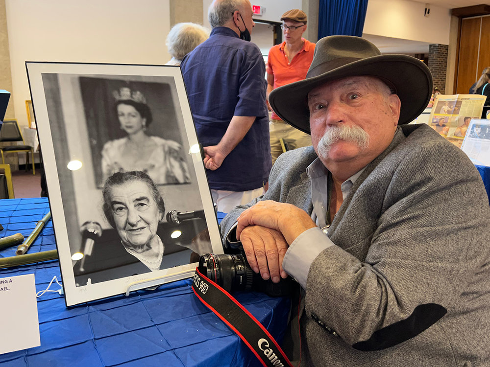 Photographer Lester Millman with his portrait of Golda Meir, former Prime Minister of Israel, with a portrait of Queen Elizabeth II behind her.