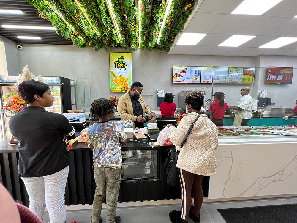 Customers await their food on the opening day of Golden Krust.