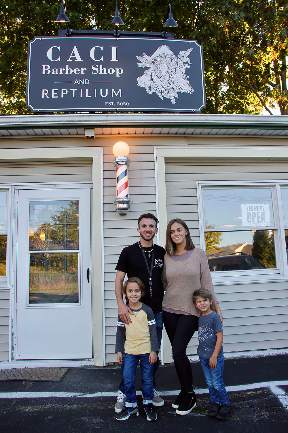 Vincenzo “Chenzo” Caci poses with his family in front of his business, “Caci Barber Shop and Reptilium” on Route 9W, Highland. Clients here can get a haircut and “talk reptiles” with Chenzo, who houses a multitude of lizards and snakes in glass terraria right in the shop!
Pictured here in the top row (left to right): Chenzo Caci and wife Krystle. Bottom row: sons Sebastiano (left) and Massimo (right).