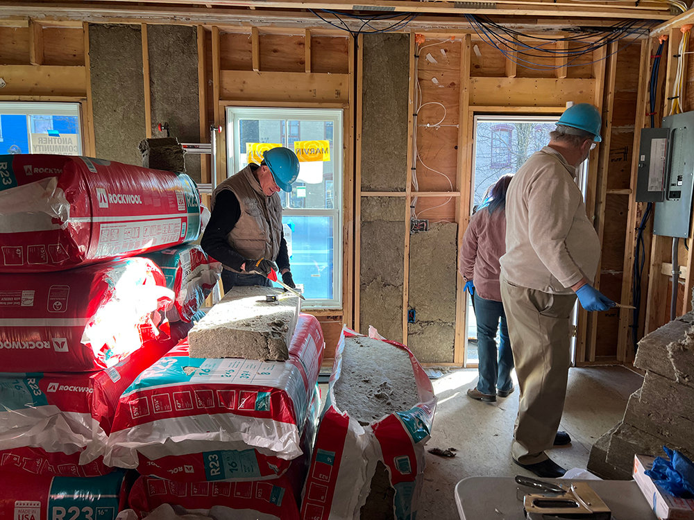 Paul Brothe (left) helps prepare insulation to be installed at 139 Johnston Street.