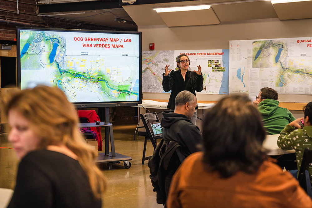 Gita Nandan of Thread Collective [standing] shares and speak on a map of the creek with the public during the forum.