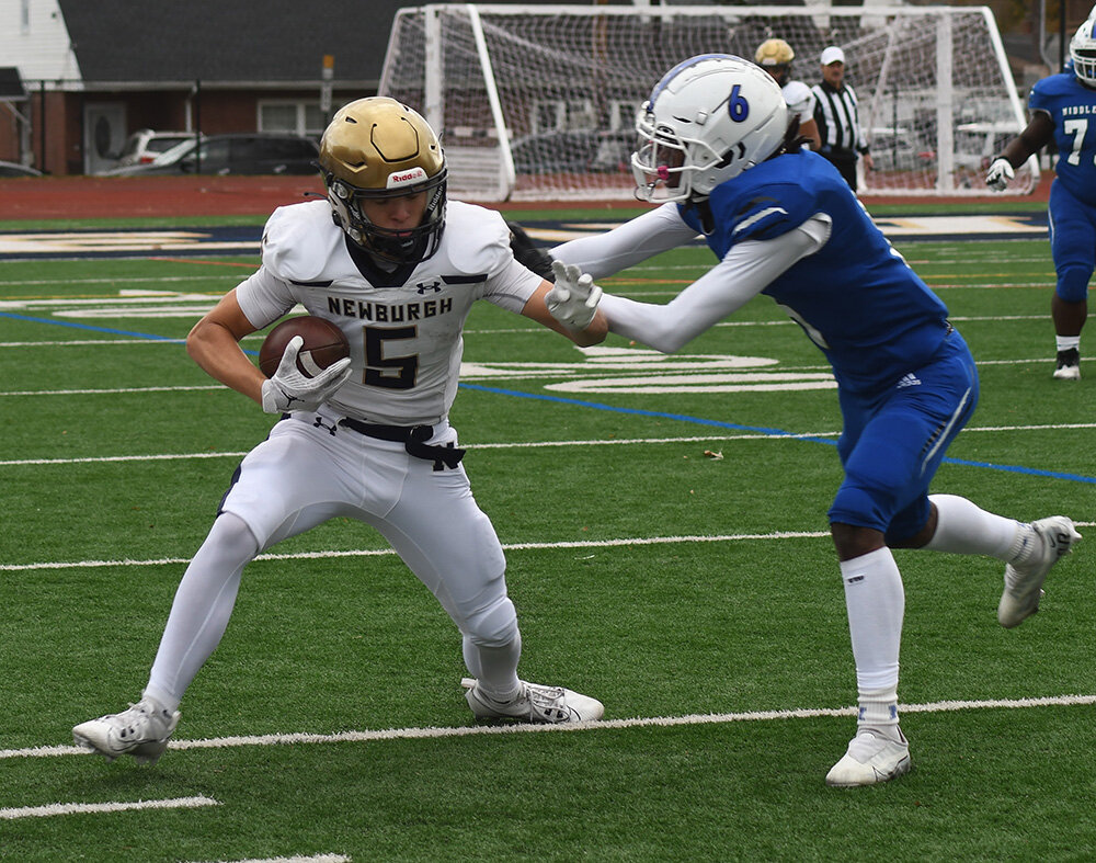 Newburgh's Jun Rivas picks up some additional yards as Middletown's Kaden Blackman tries to bring him down during Saturday's Section 9 Class AA championship football game at Academy Field in Newburgh.