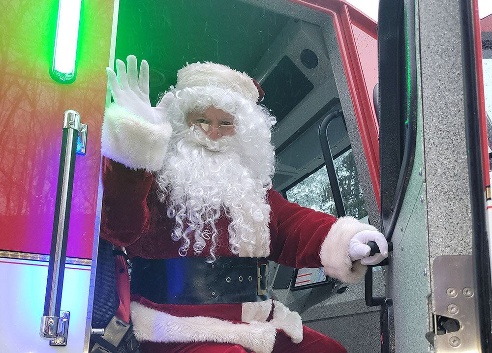 Aboard the Milton fire company engine, “Santa” (Greg Lobdell) waves goodbye to visitors to the annual Milton tree-lighting ceremony on December 3.